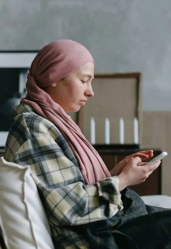 Femme portant un foulard rose et consultant son smartphone à domicile.